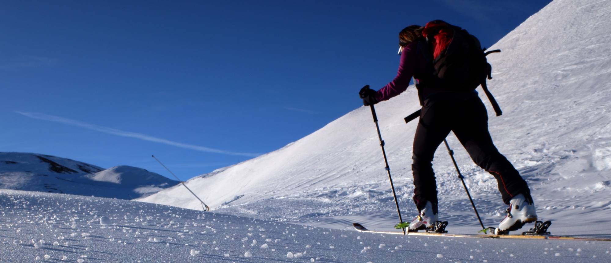 Skitourengeherin am Skipistenrand bei Sonnenschein